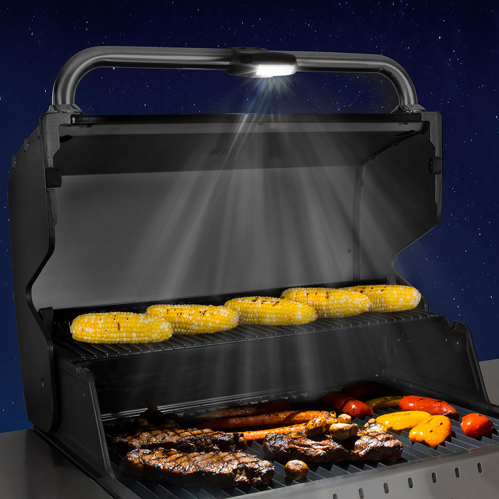 Broil King grill light illuminating corn, meat, and peppers in the grill