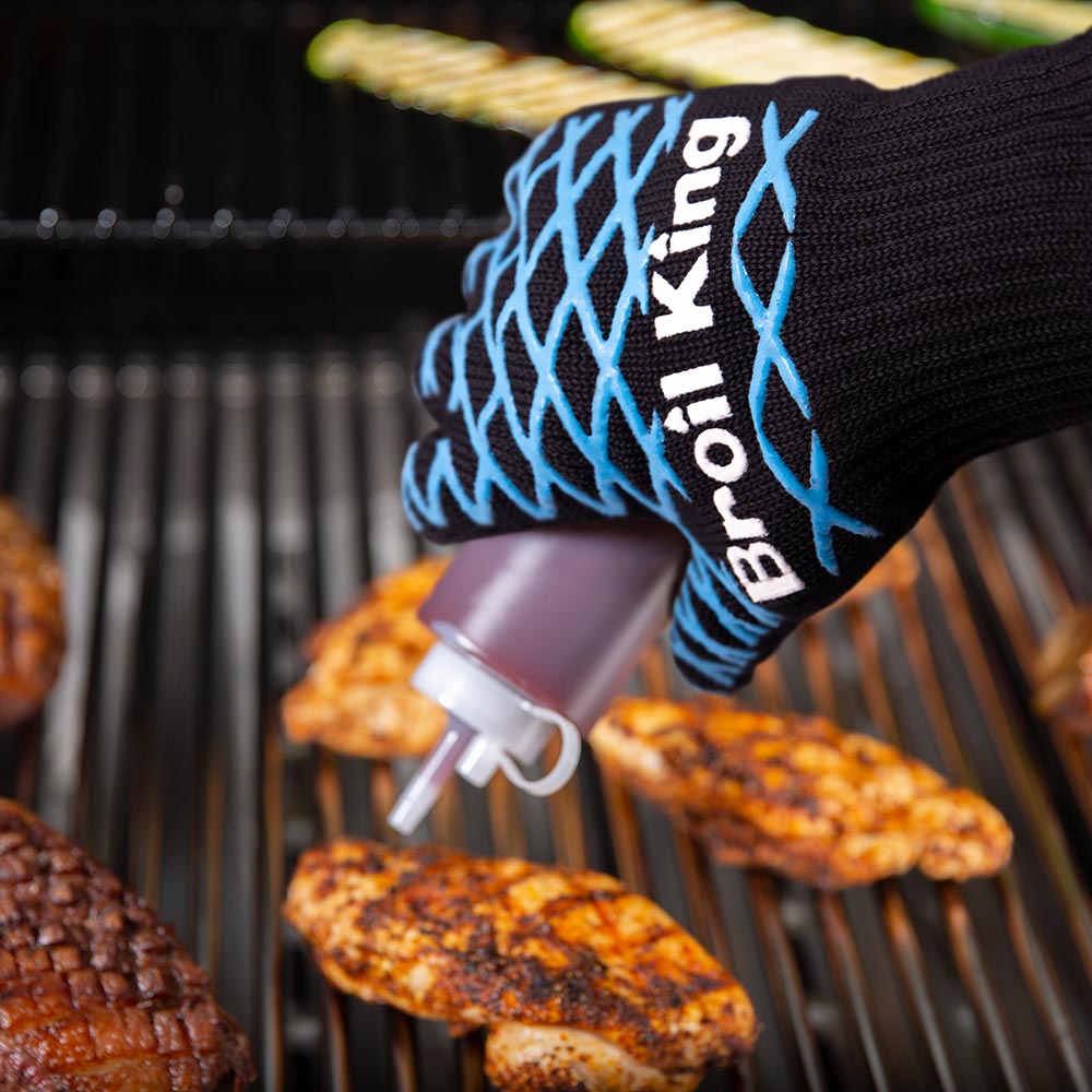 Broil King grilling mitt on hand with blue pattern, gripping metal handle