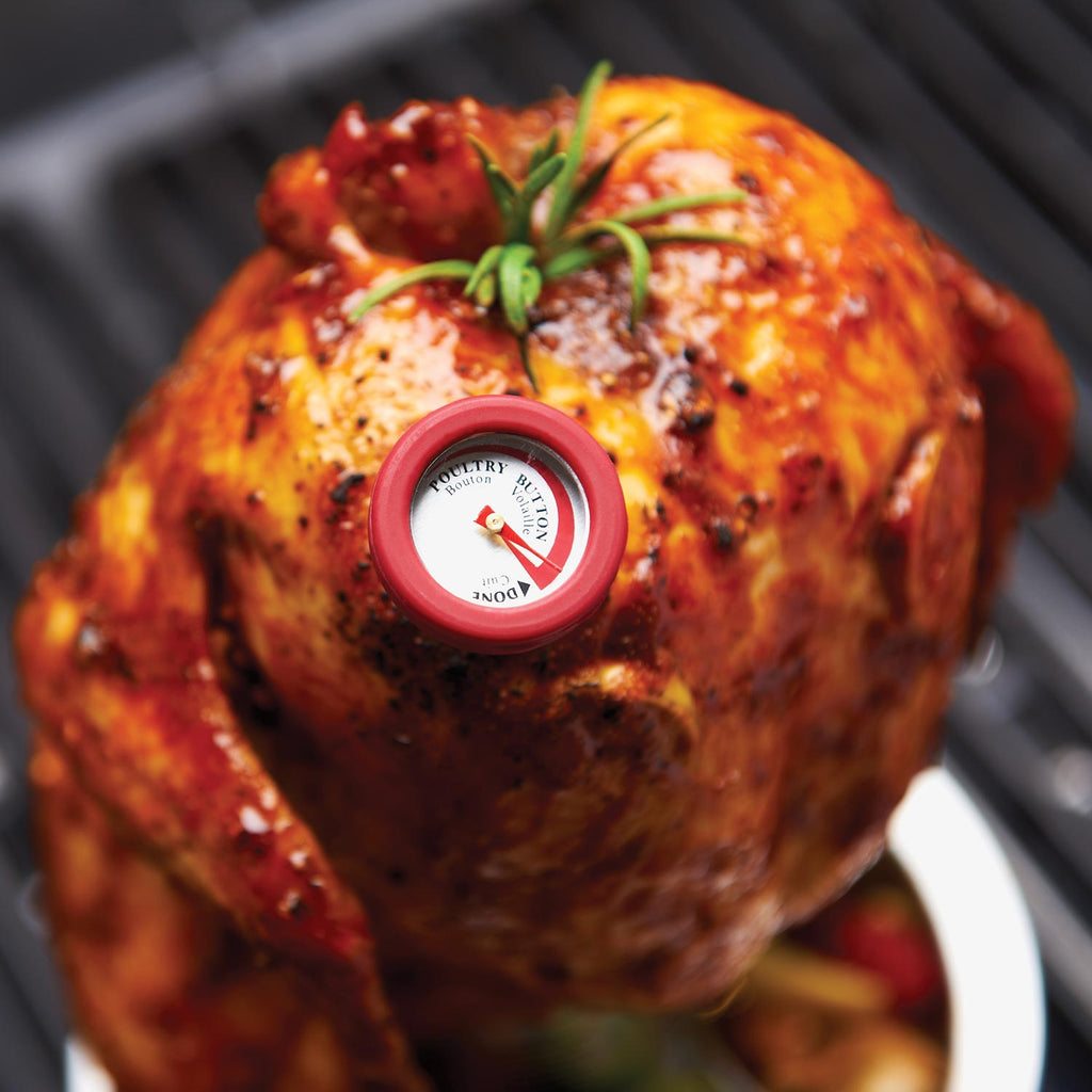 Mini thermometer with round red casing and dial on roasted chicken