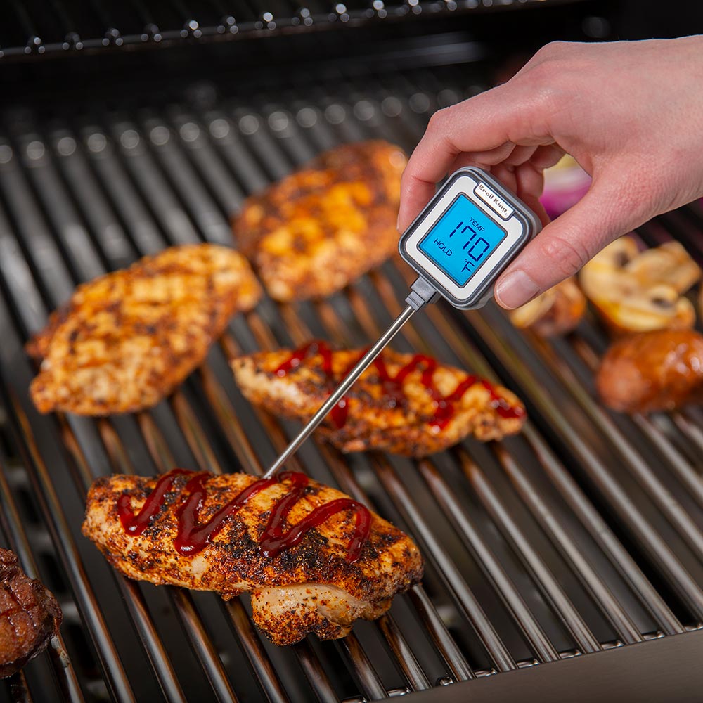 Instant read thermometer on grill grate, probe inserted in meat, blue temperature display