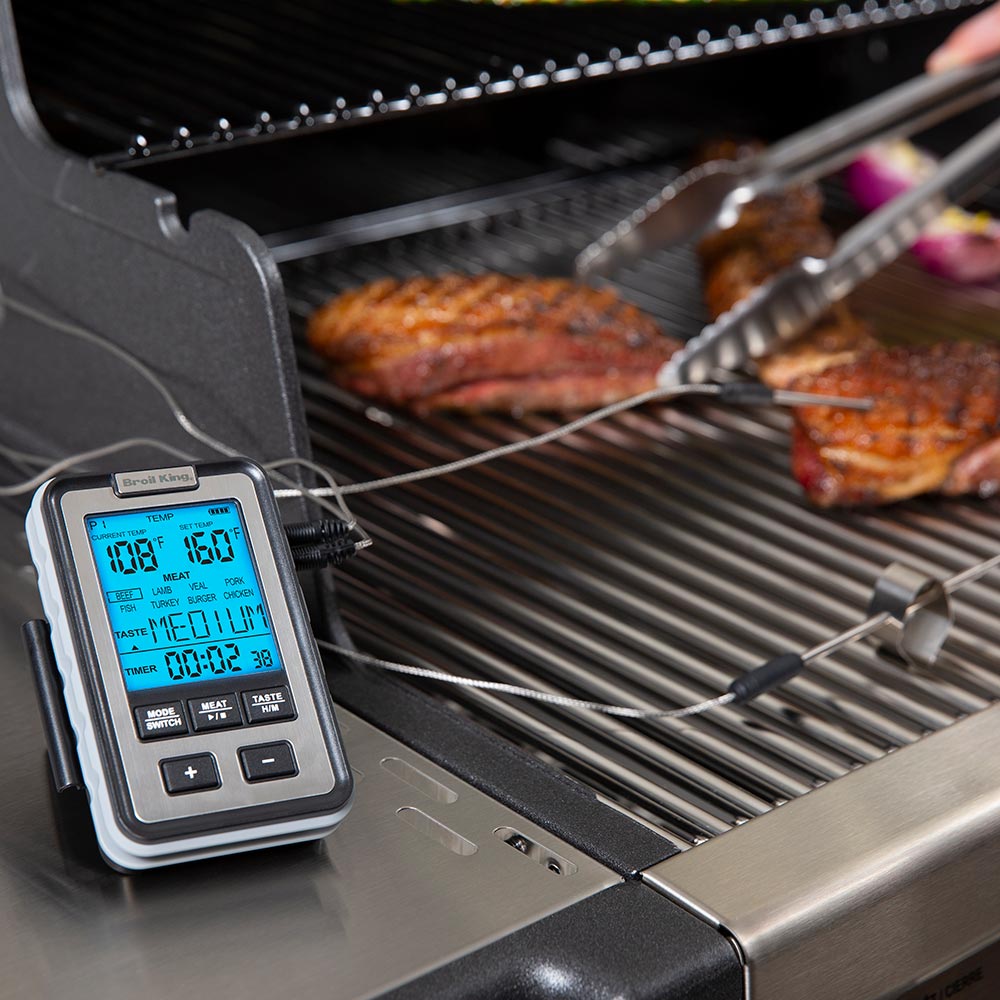 Digital meat thermometer controller on grill with two probes monitoring meat on grates