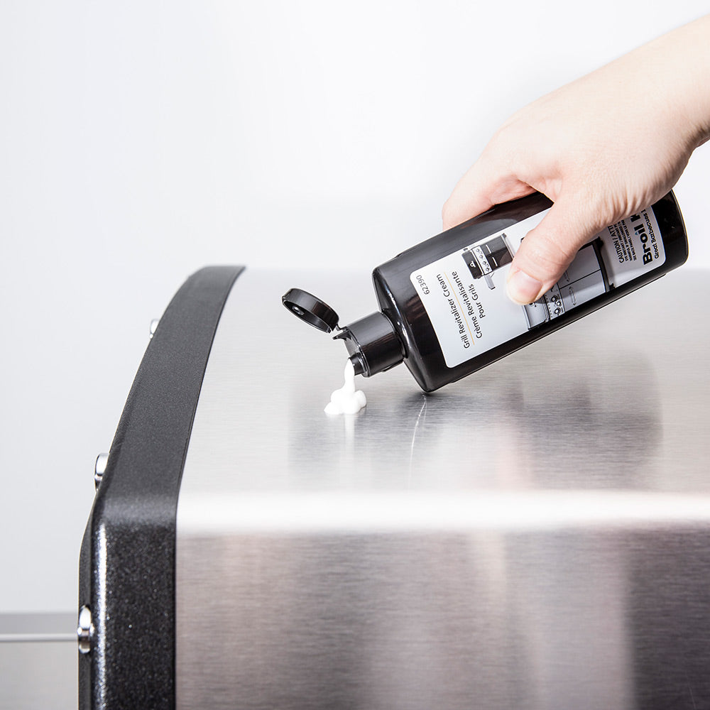 Hand spraying Broil King Grill Revitalizer Cream onto stainless grill