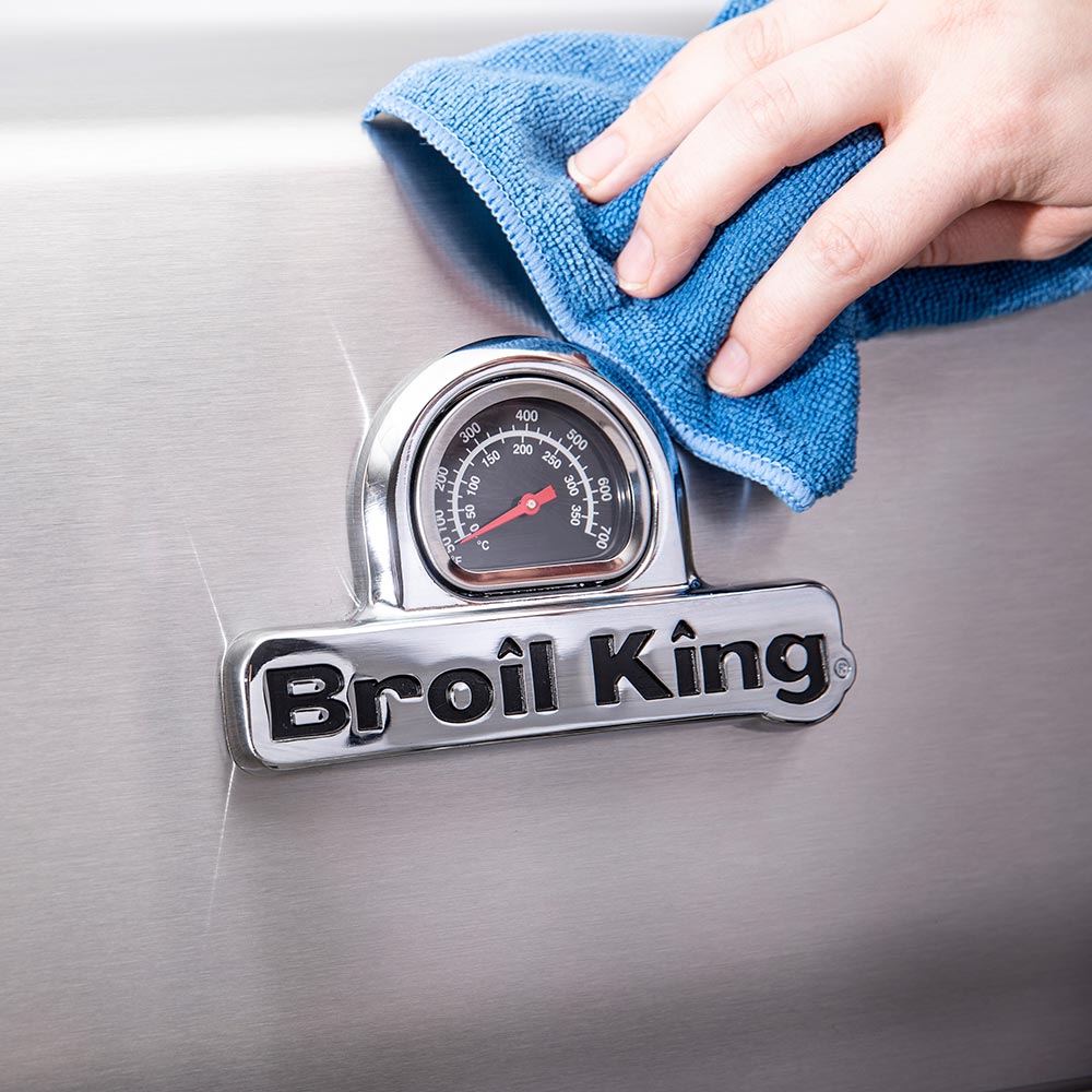 Broil King grill control area being wiped with blue cloth