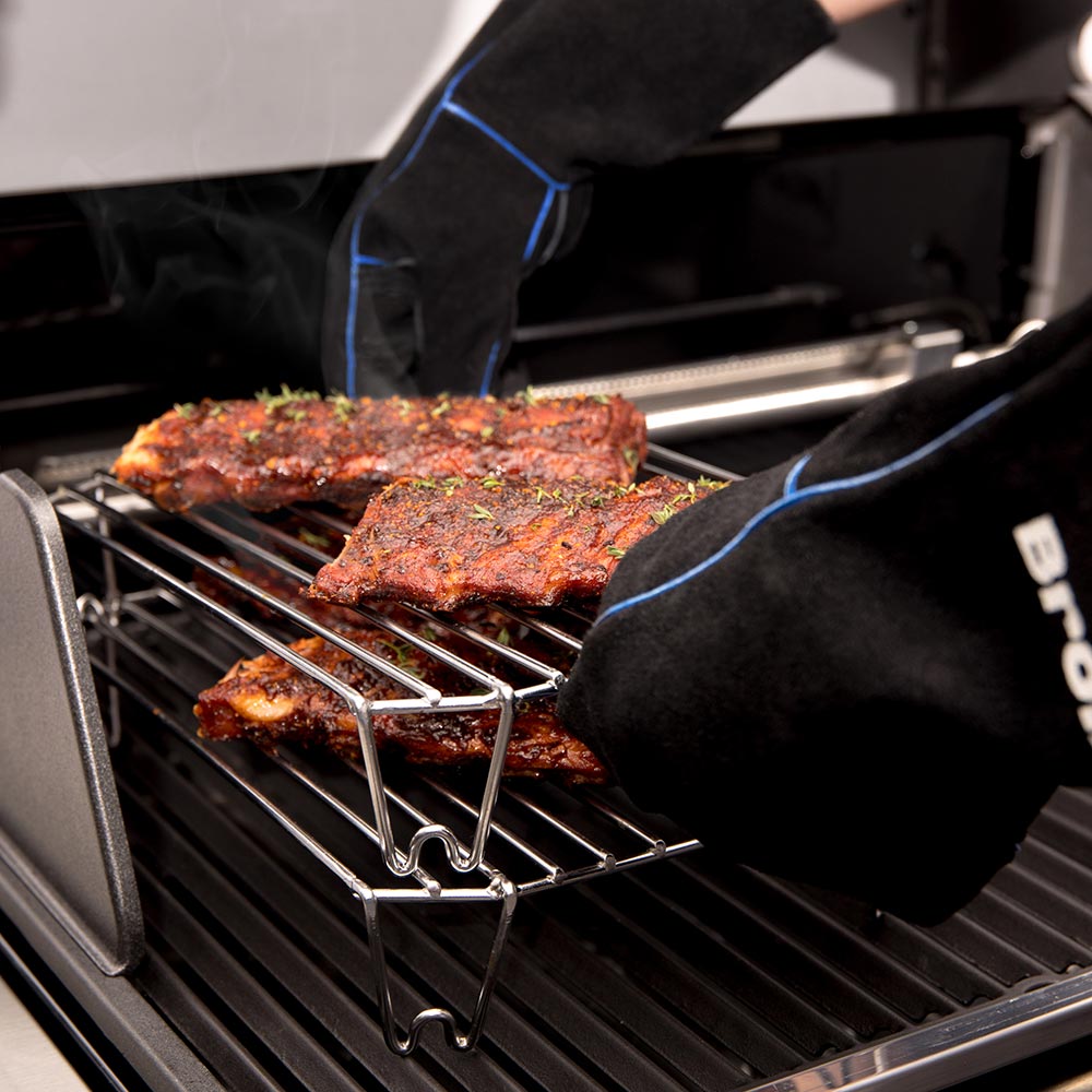 Stainless steel grilling rack with meat slabs as a cook adjusts them