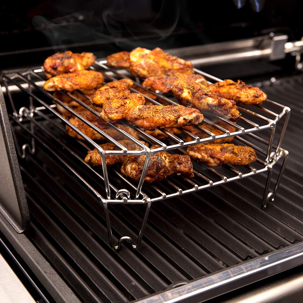 Stainless steel grilling rack with assorted meat pieces stacked on wire bars