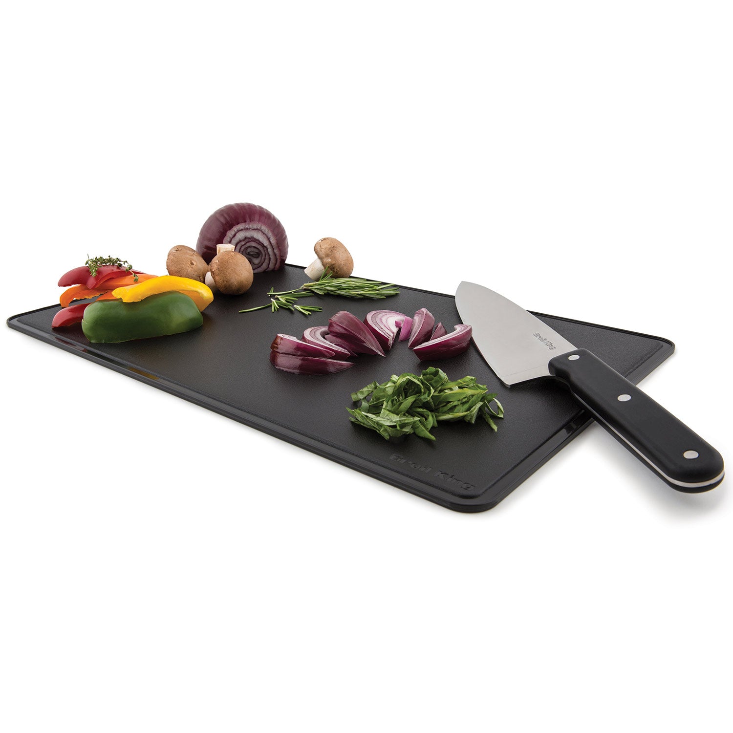 Black cutting board with chef knife and mixed vegetables and herbs
