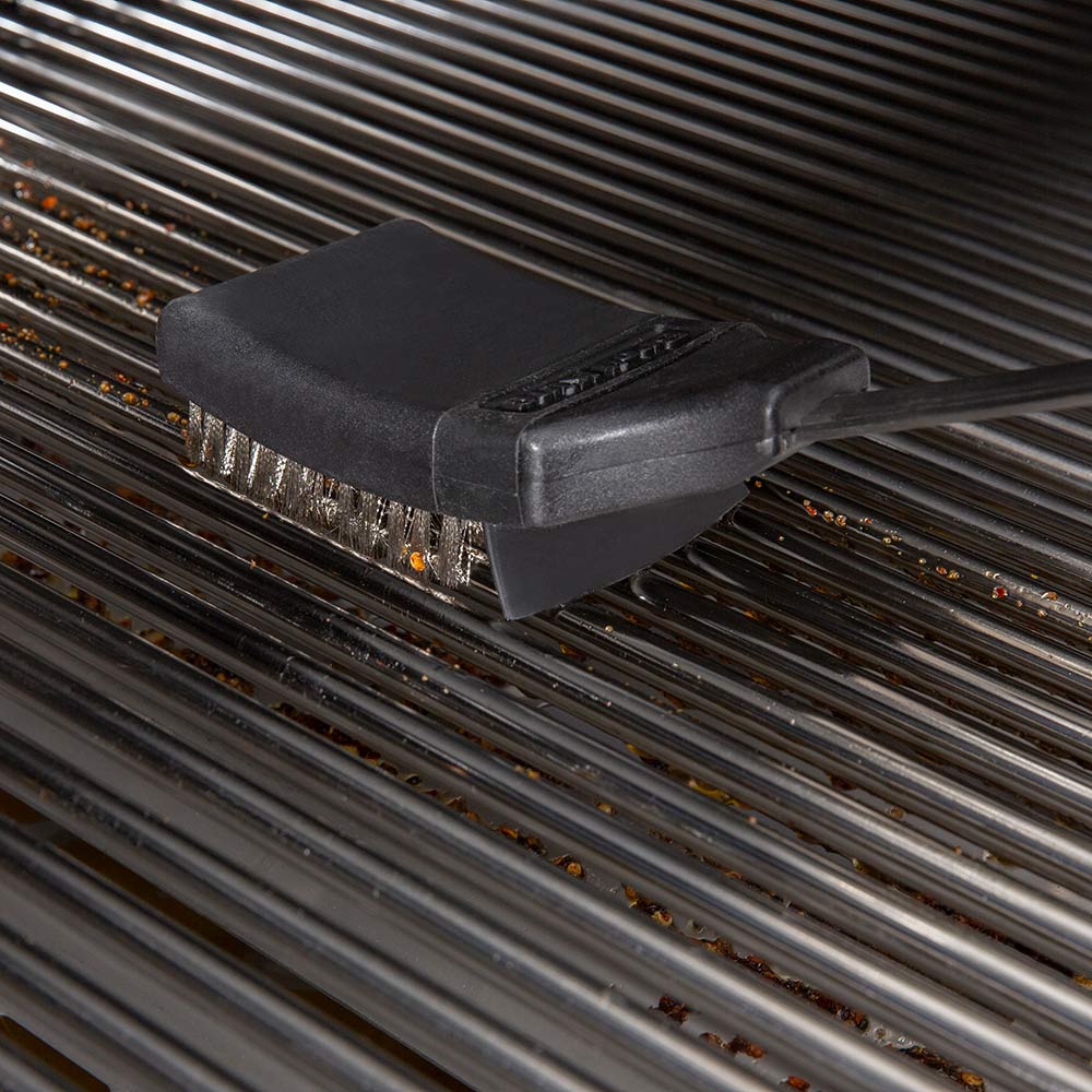 Grill brush with black head cleaning metal grill grates.
