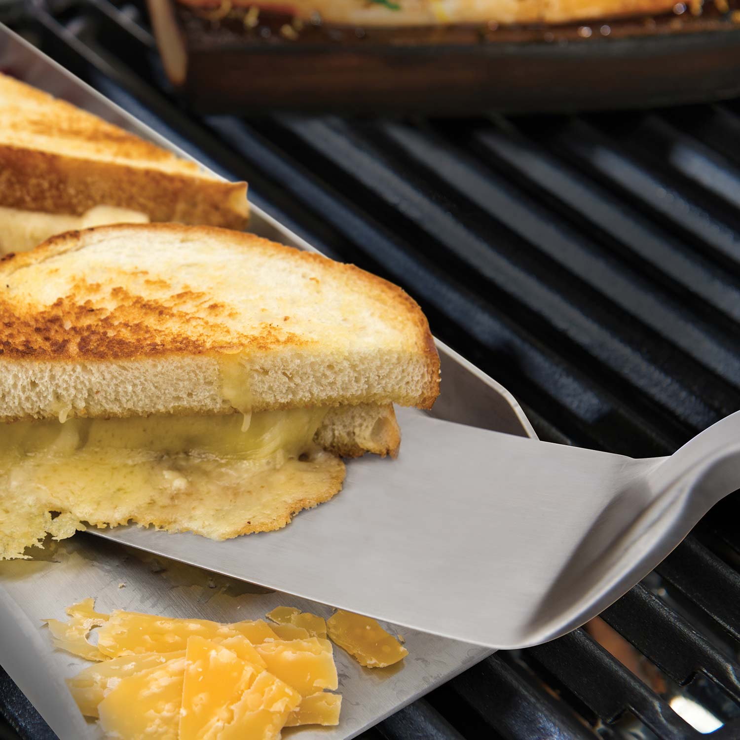 Grill turner lifting bread and cheese on grates, stainless head