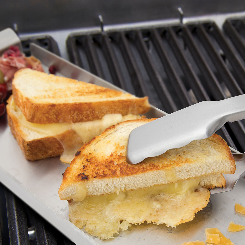 Broil King grill tongs lifting toasted bread on a grill tray with melted cheese.