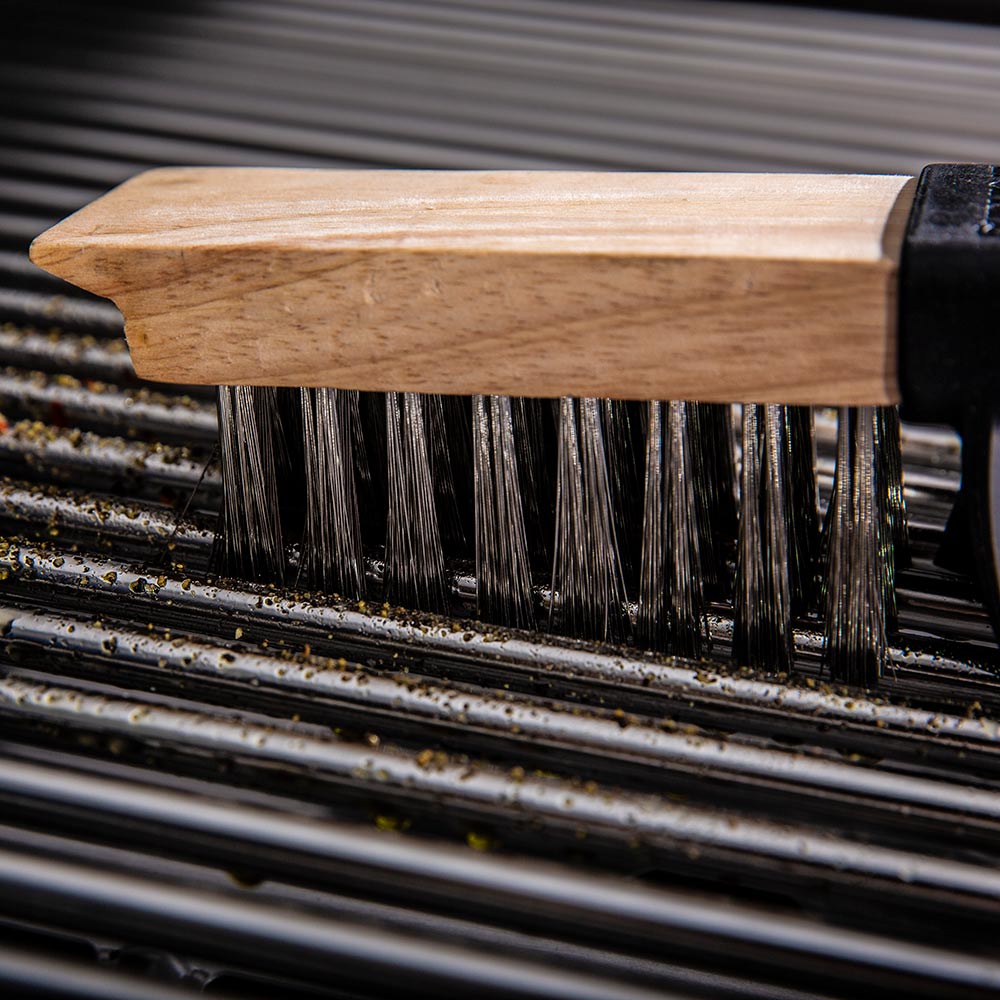 Wood-handled grill brush bristles on black grill grates