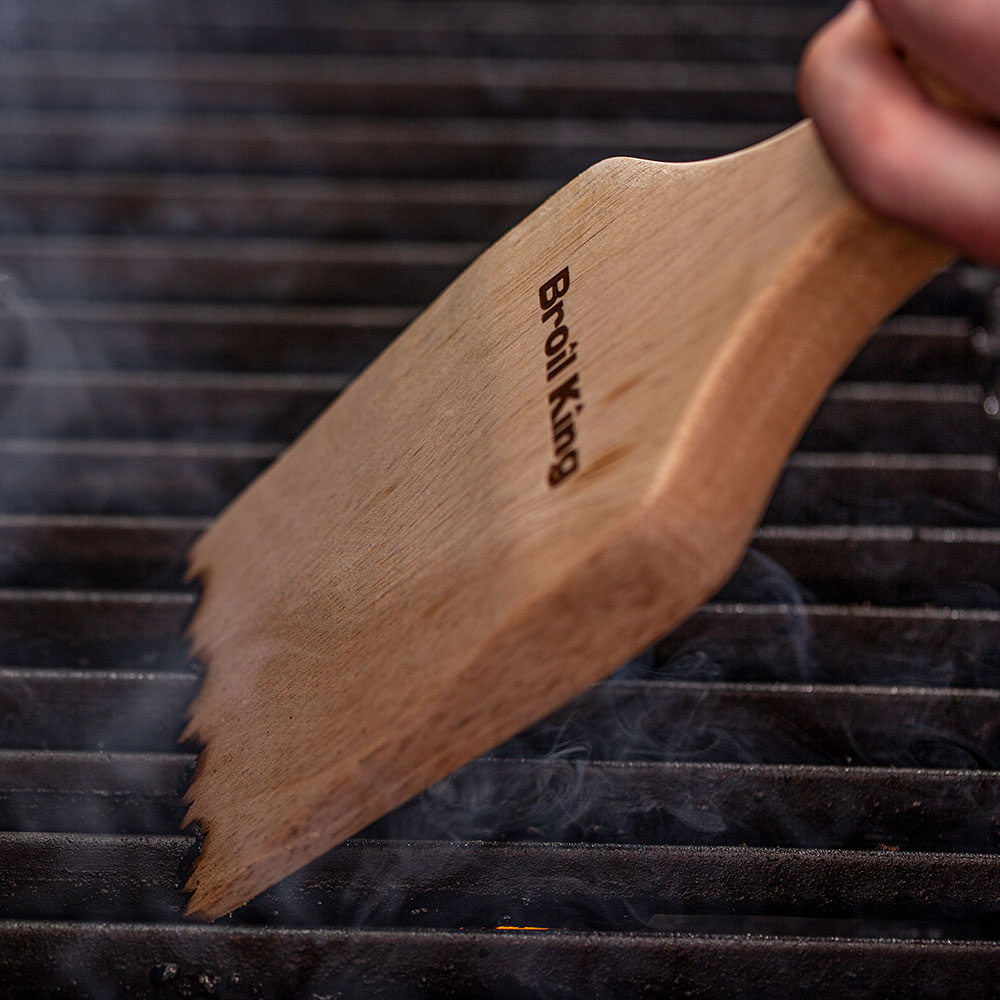 Wood grill scraper on grill grates, Broil King logo on handle