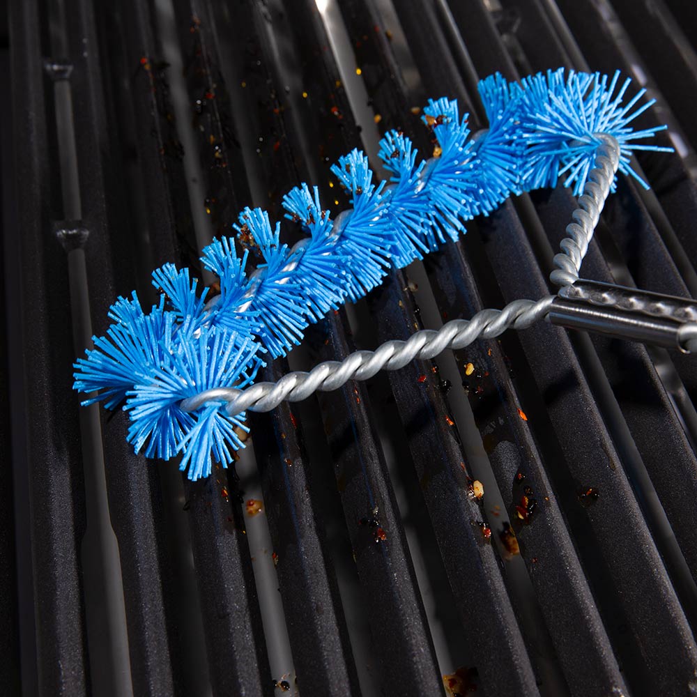 Grill brush with blue nylon bristles scrubbing black metal grates