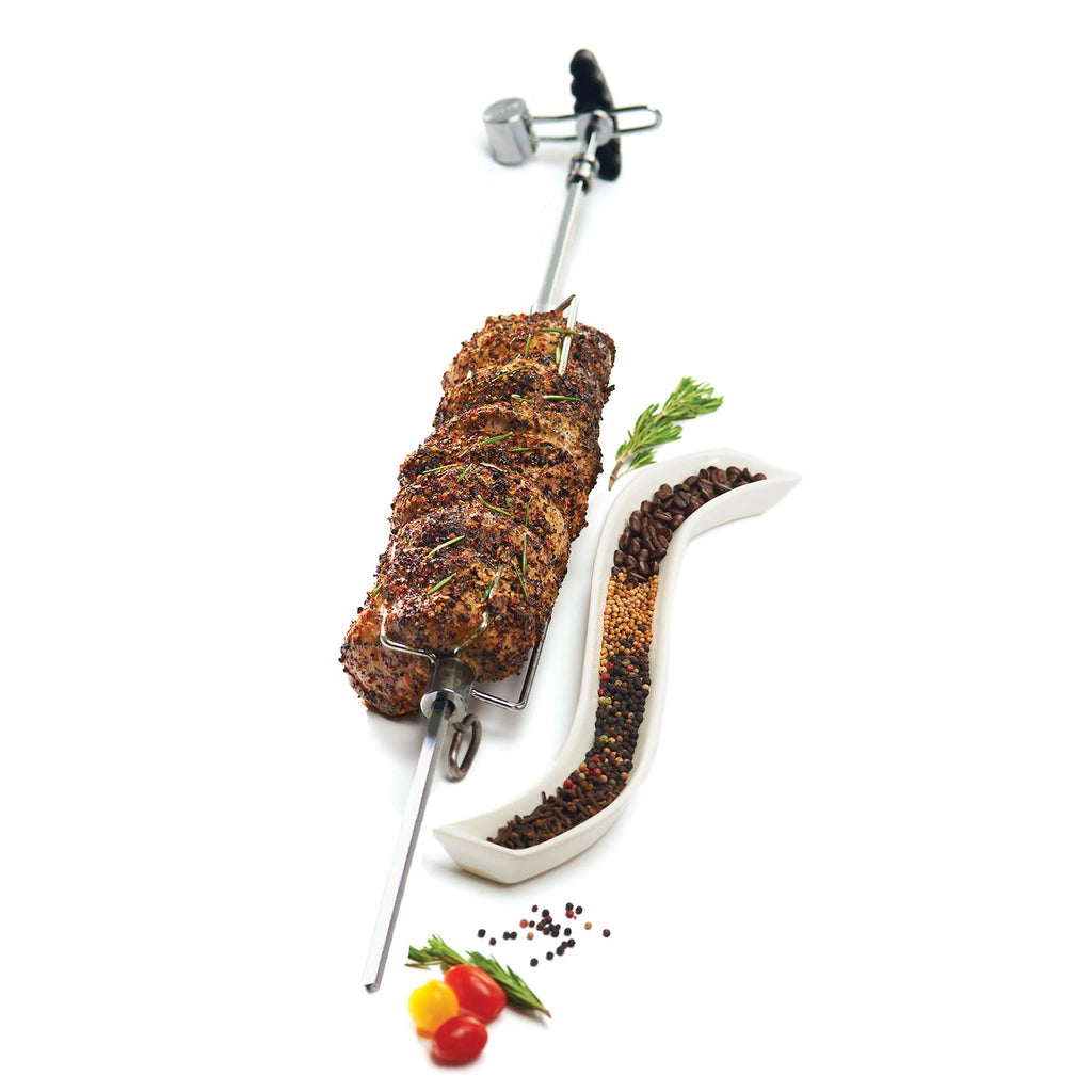Rotisserie roast on spit with herbs, tomato, and scattered seasonings