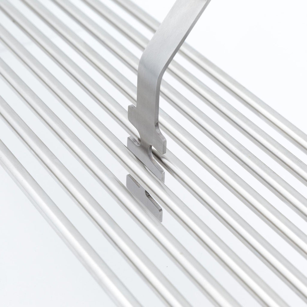 Broil King grid lifter with metal prongs on silver grill grates
