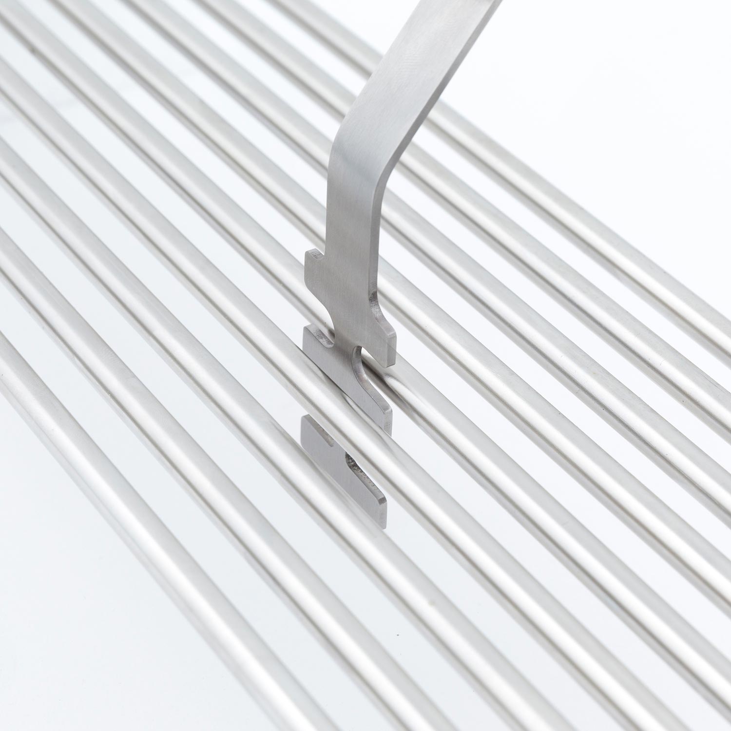 Broil King grid lifter with metal prongs on silver grill grates