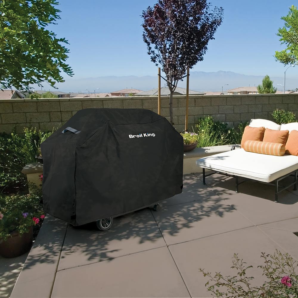 Broil King grill cover, dark gray, draped over an outdoor wheeled grill