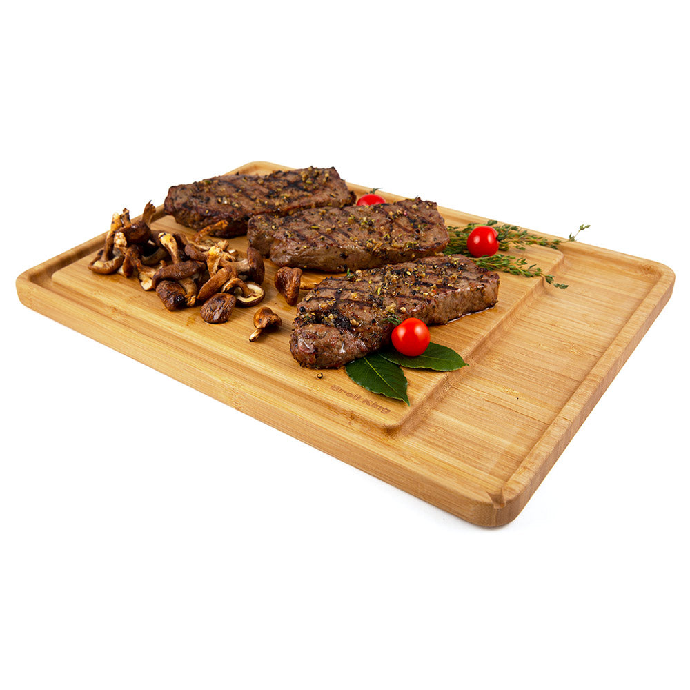 Bamboo cutting and serving board with sliced grilled meat, mushrooms, and tomatoes
