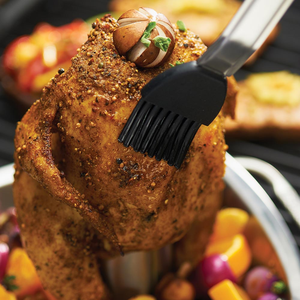 Chicken roaster pan with upright basket and brush-style handle, with roasted chicken