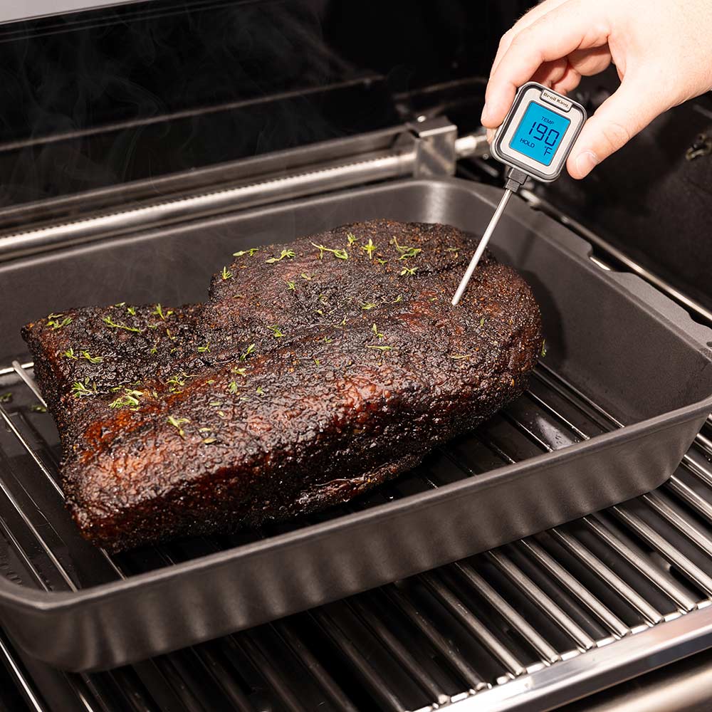 Cast iron multi roaster with thermometer probe inserted into seasoned roast on rack