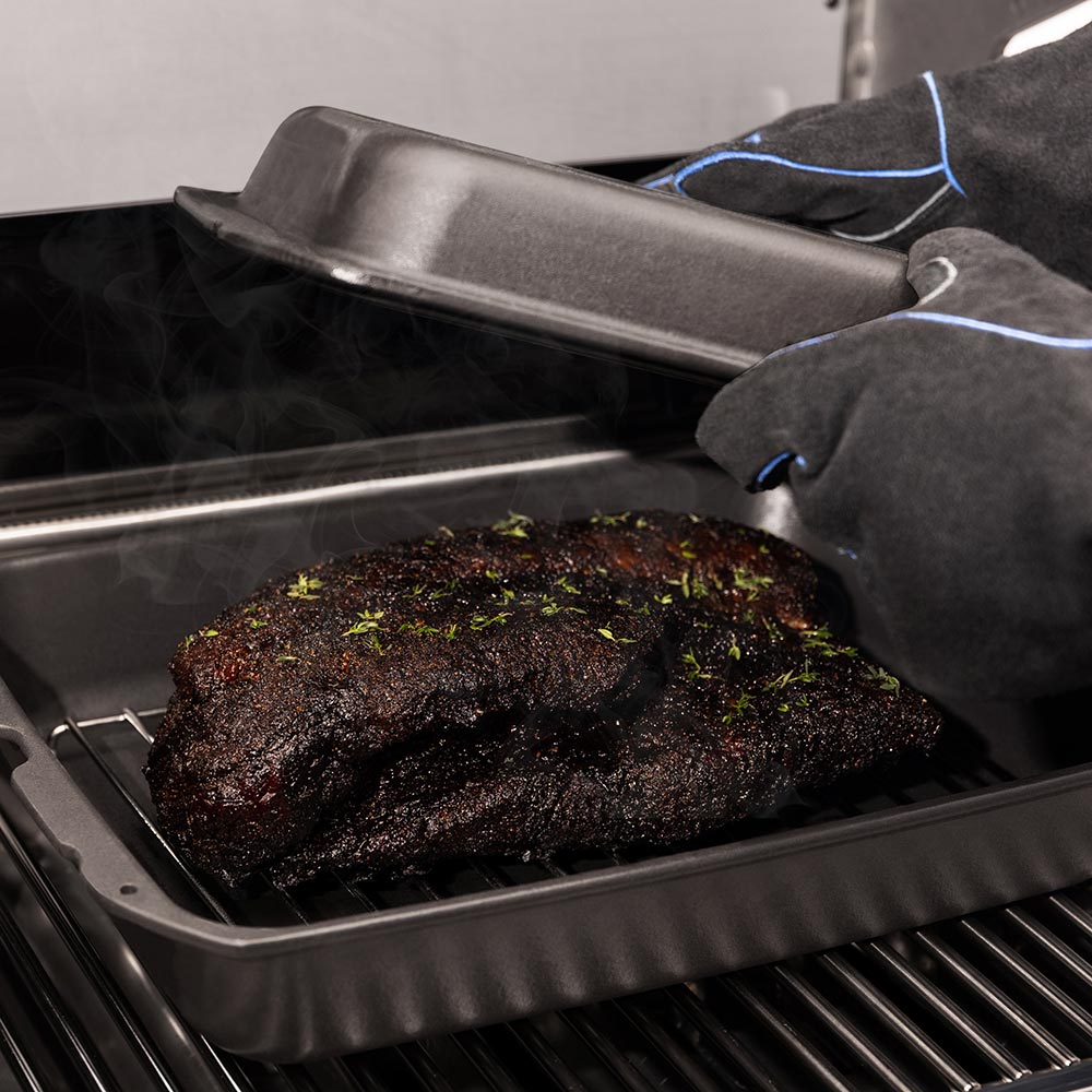 Cast iron multi roaster with roast in tray, lid lifted by gloved hand