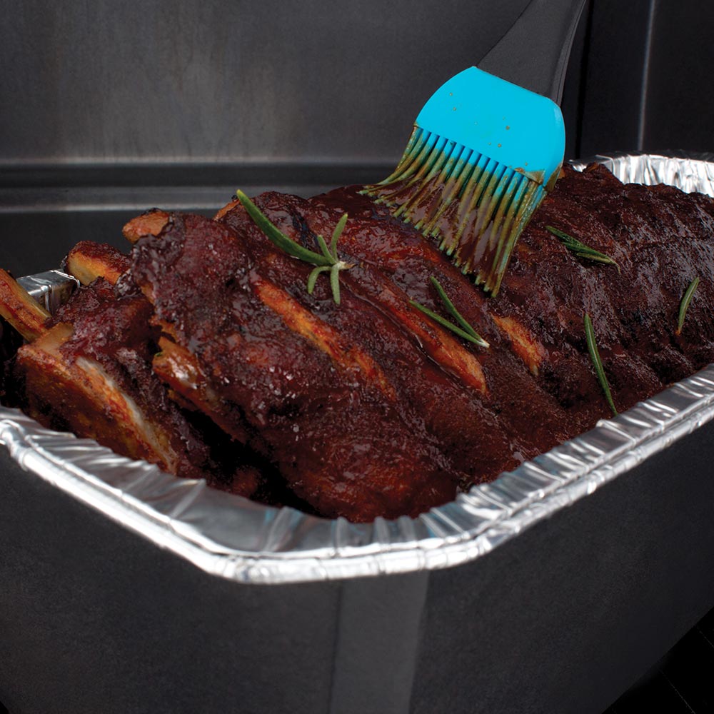 Foil roaster liner filled with ribs, brushed with sauce