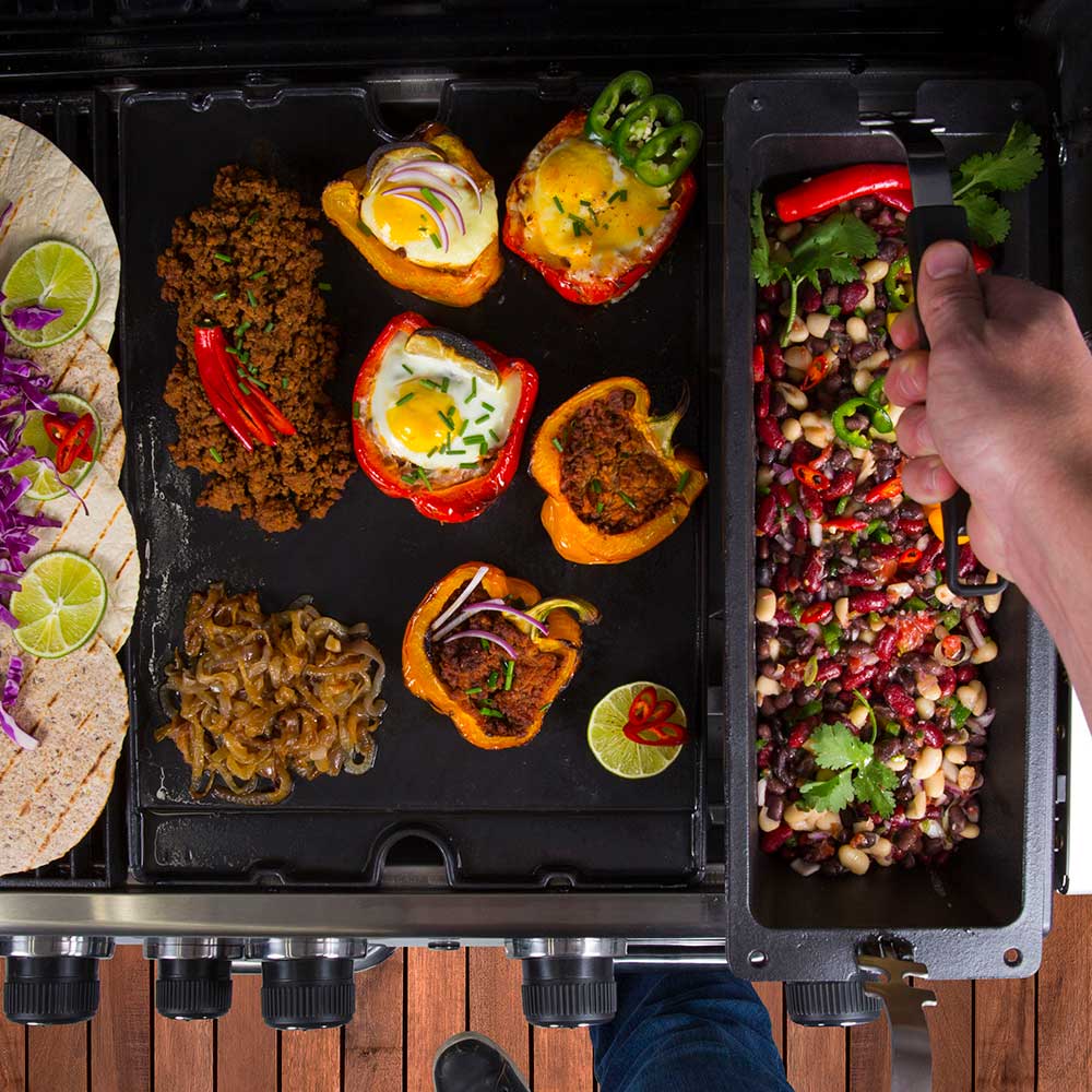 Cast iron wok insert with mixed grilled food and a hand reaching in