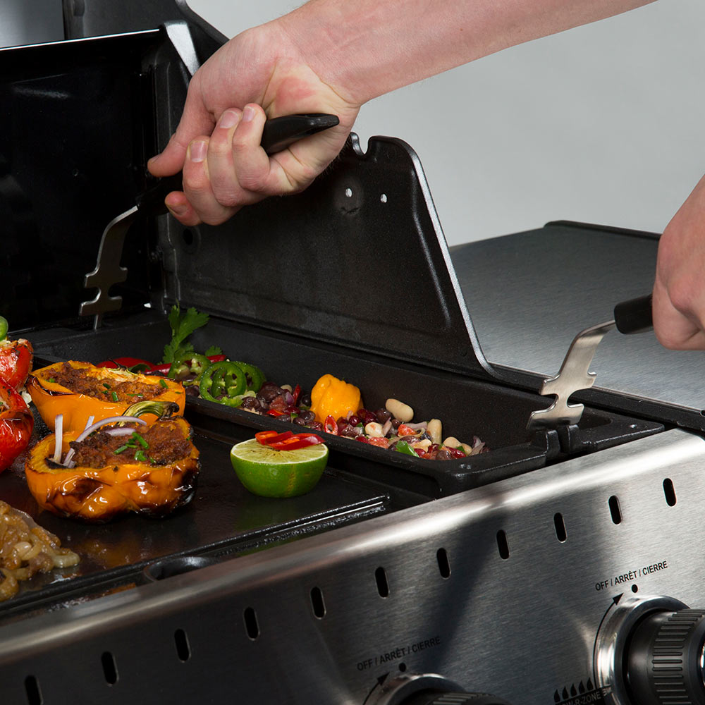 Cast iron wok insert on grill with seafood and peppers, lid being adjusted