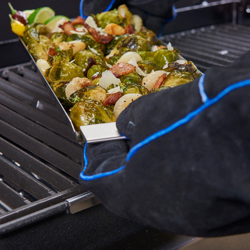 Narrow stainless steel grill topper tray with roasted vegetables on an outdoor grill