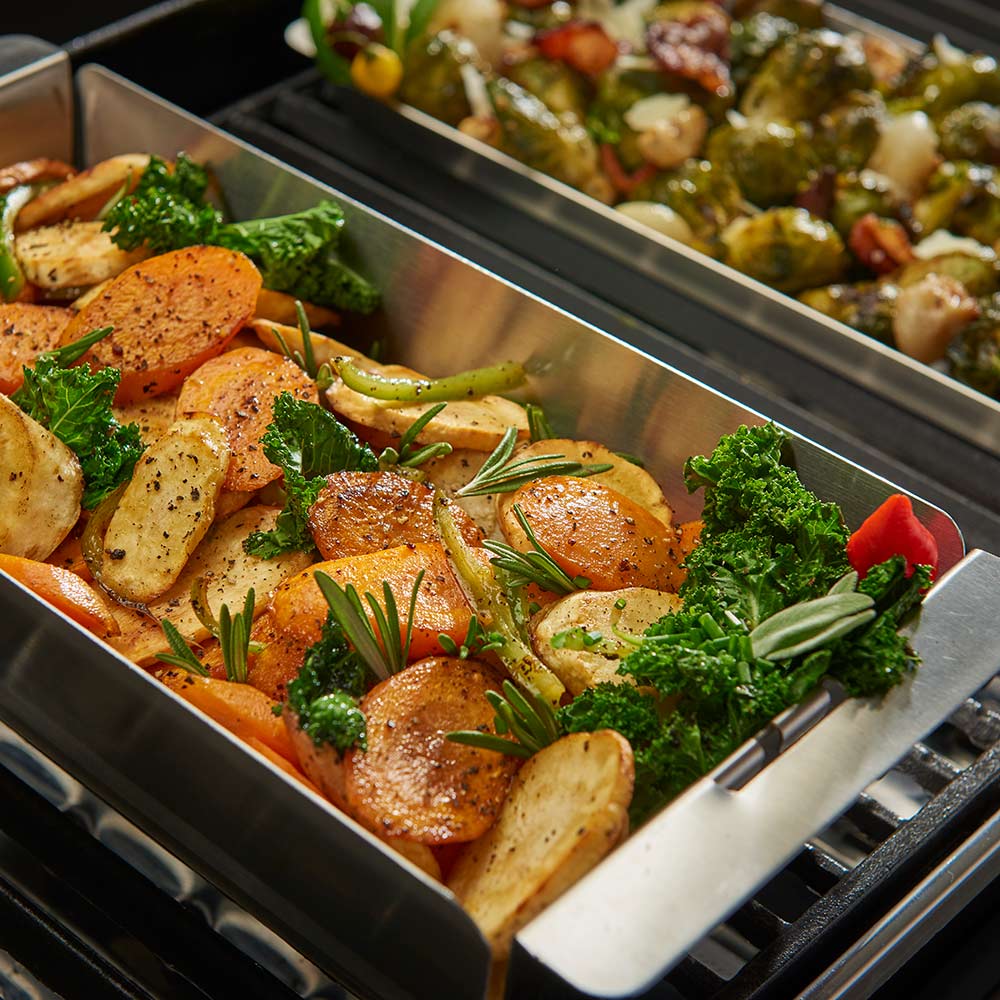Stainless steel wok grill topper on grill filled with roasted vegetables
