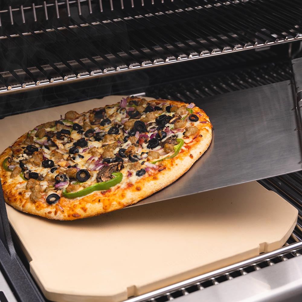 Rectangular pizza stone with pizza on top on grill rack, beige stone