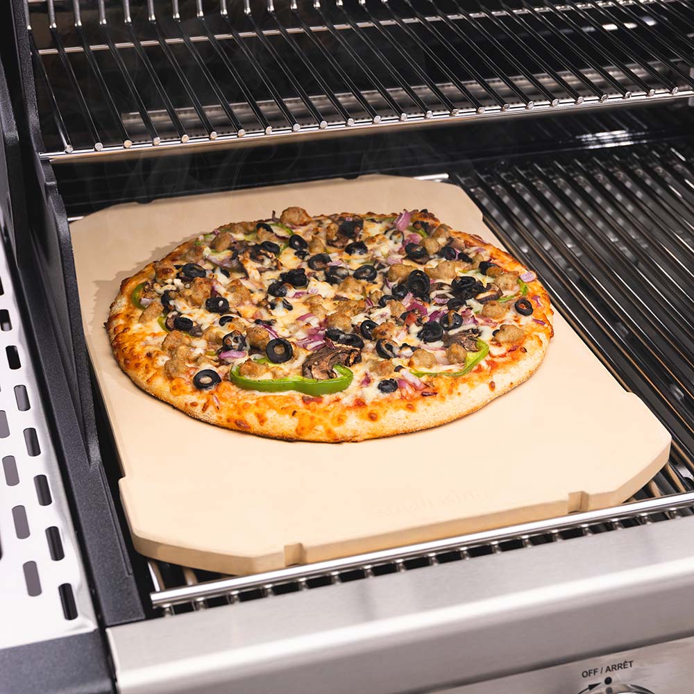 Rectangular pizza stone with pizza on top, beige surface and corner support guards