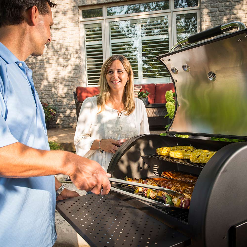 Broil King charcoal smoker grill with open lid and cooking food on grates