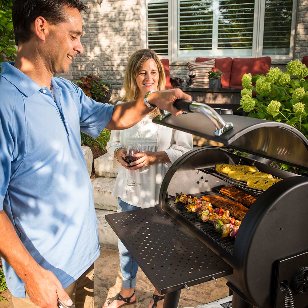 Charcoal smoker grill with open cooking chamber and food on grates