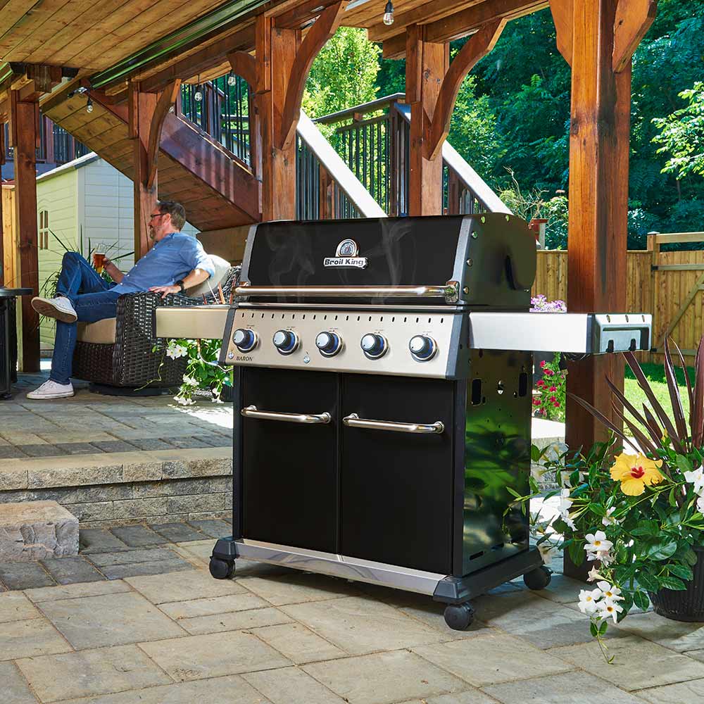 5-burner gas grill standing outdoors on legs with lid open