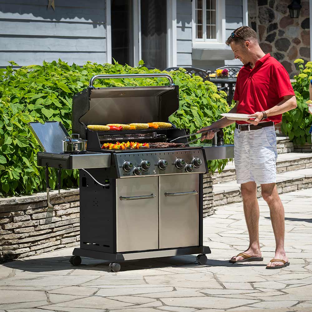 Outdoor stainless steel gas grill with open lid grilling food