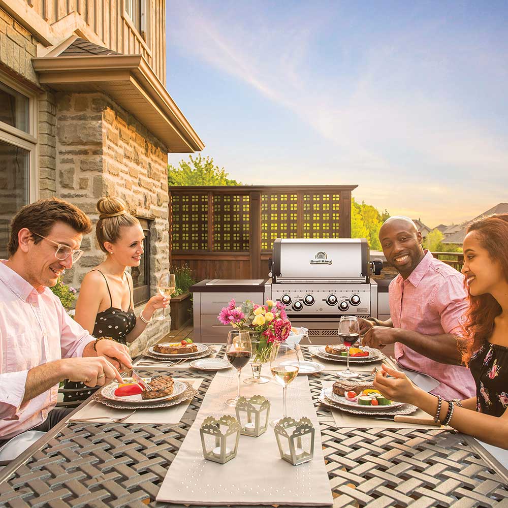 Outdoor built-in gas grill with closed hood and control knobs on patio