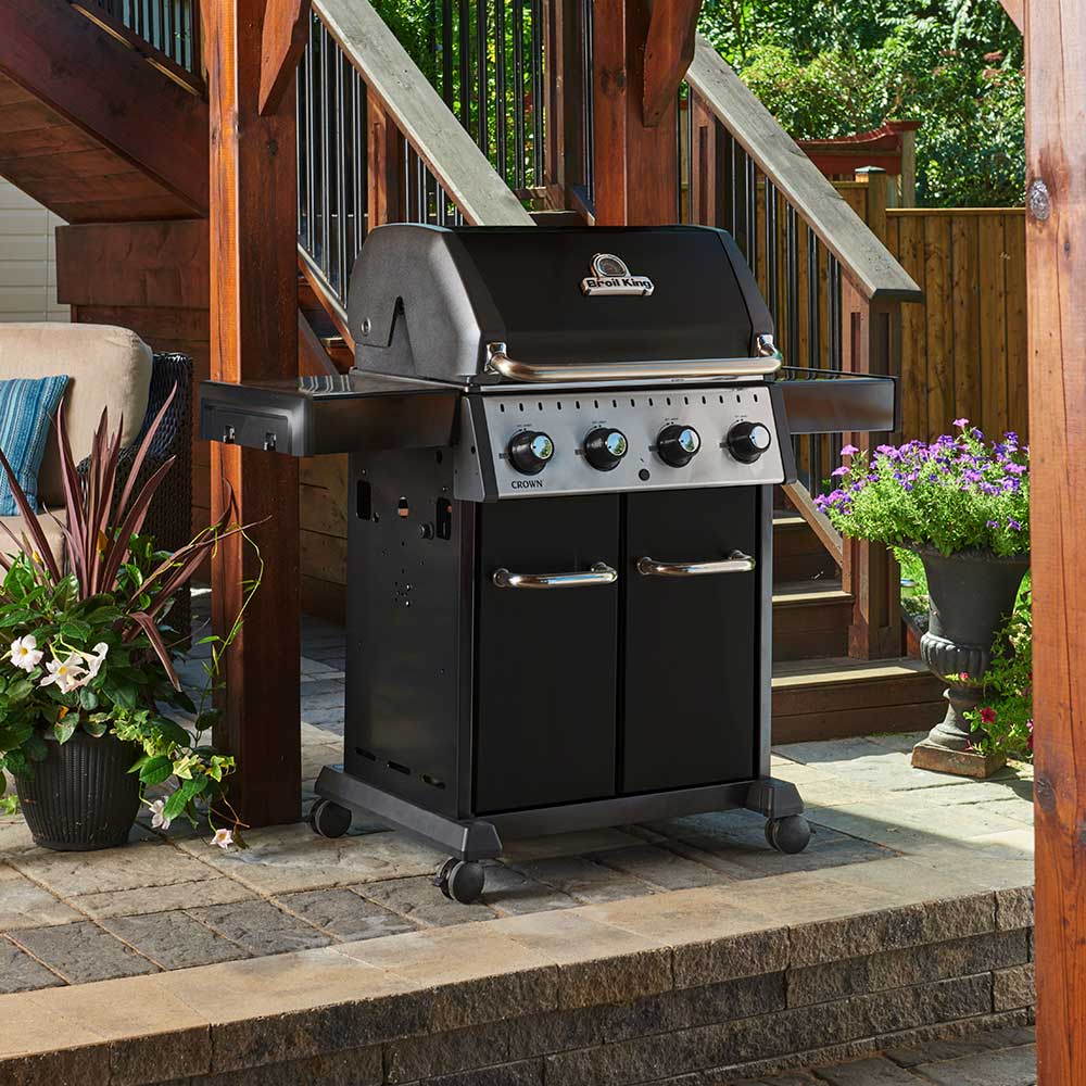 Black 4-burner gas grill on patio with open hood and cooking grates visible