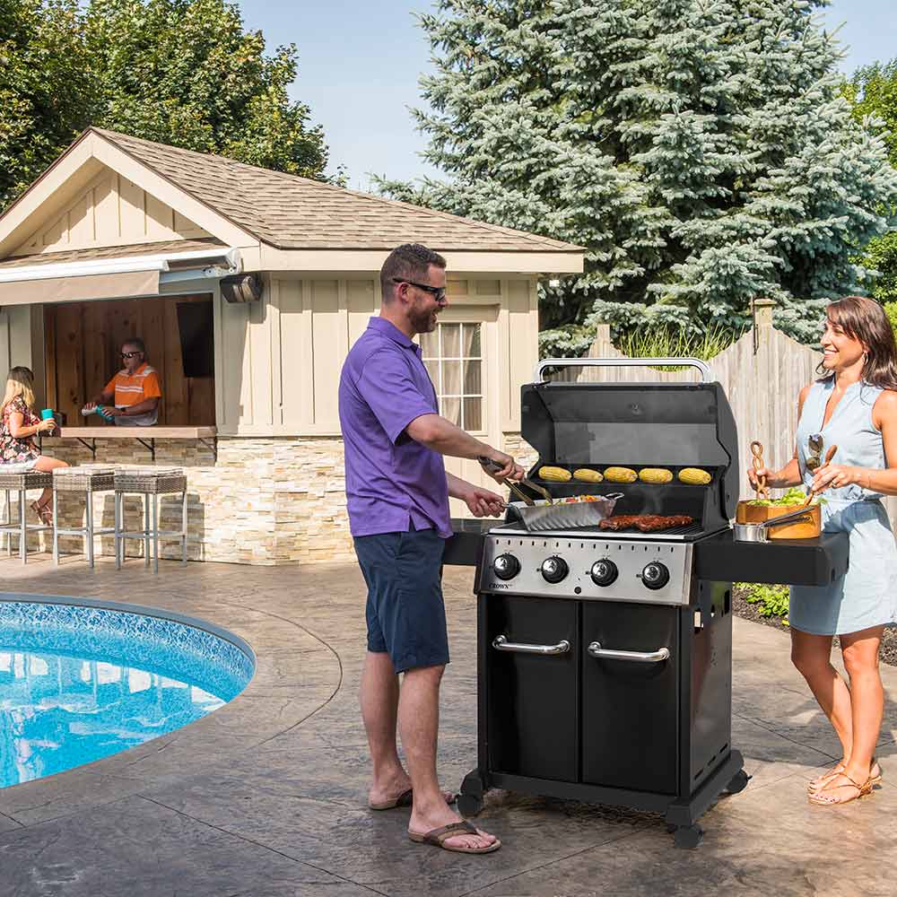 Black 4-burner gas grill in use with food on grates and front control knobs
