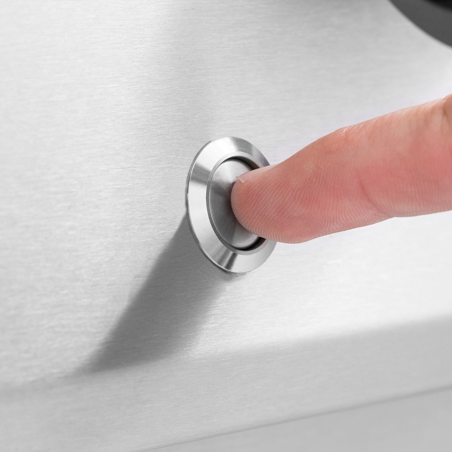 Hand pressing a round control knob on a stainless steel gas grill head