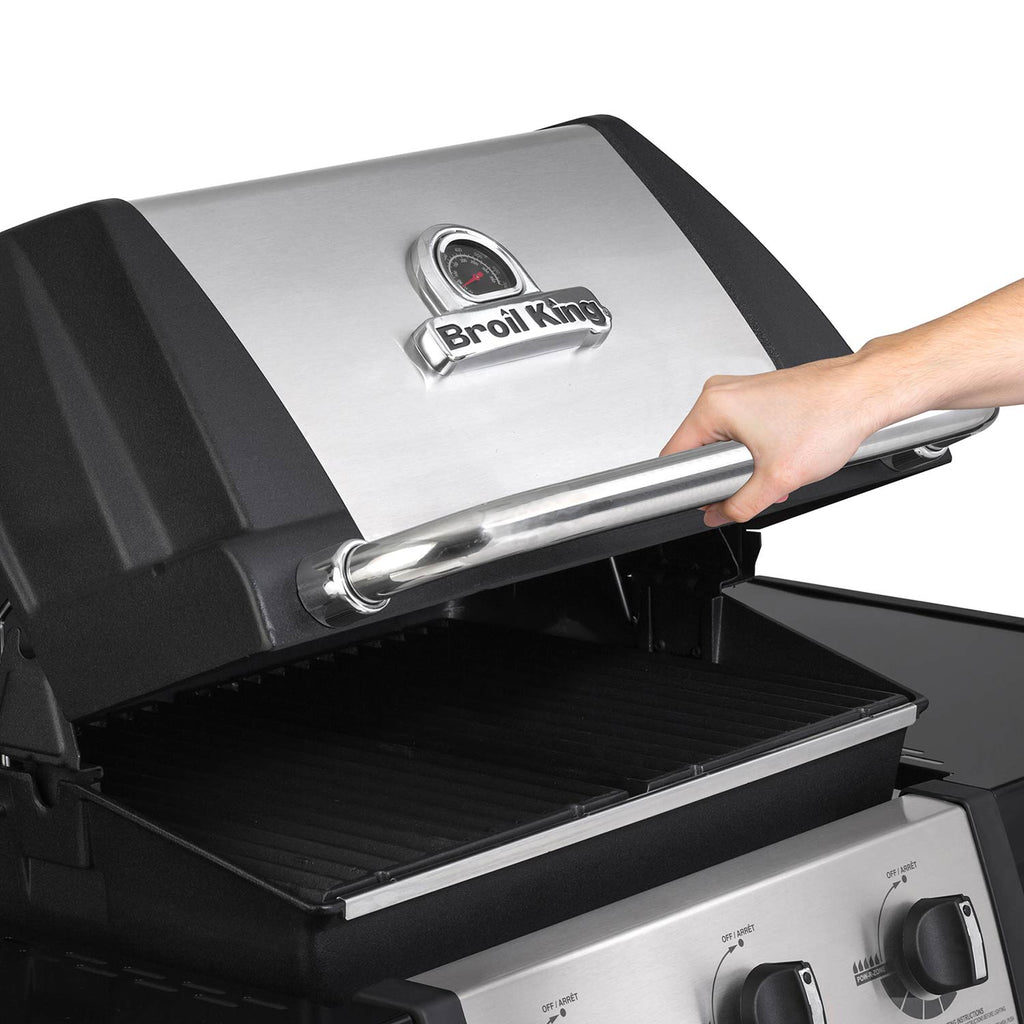 Grill lid handle and temperature gauge on the stainless hood over the cooking area