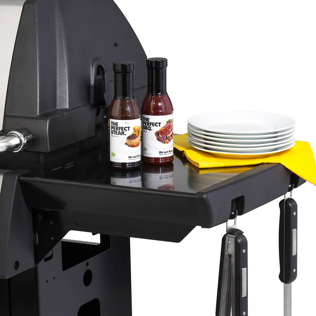 Grill side shelf with condiment bottles and stacked plates next to the grill body