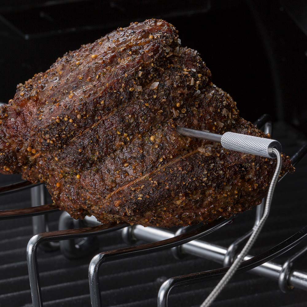 Seasoned meat roast on pellet grill grate with temperature probe