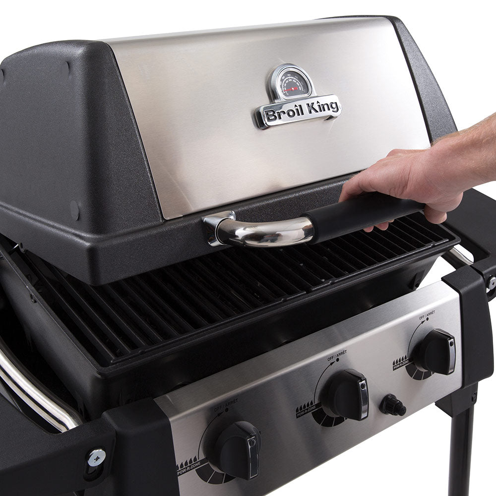 Broil King portable propane grill with lid open and side handle over the griddle surface