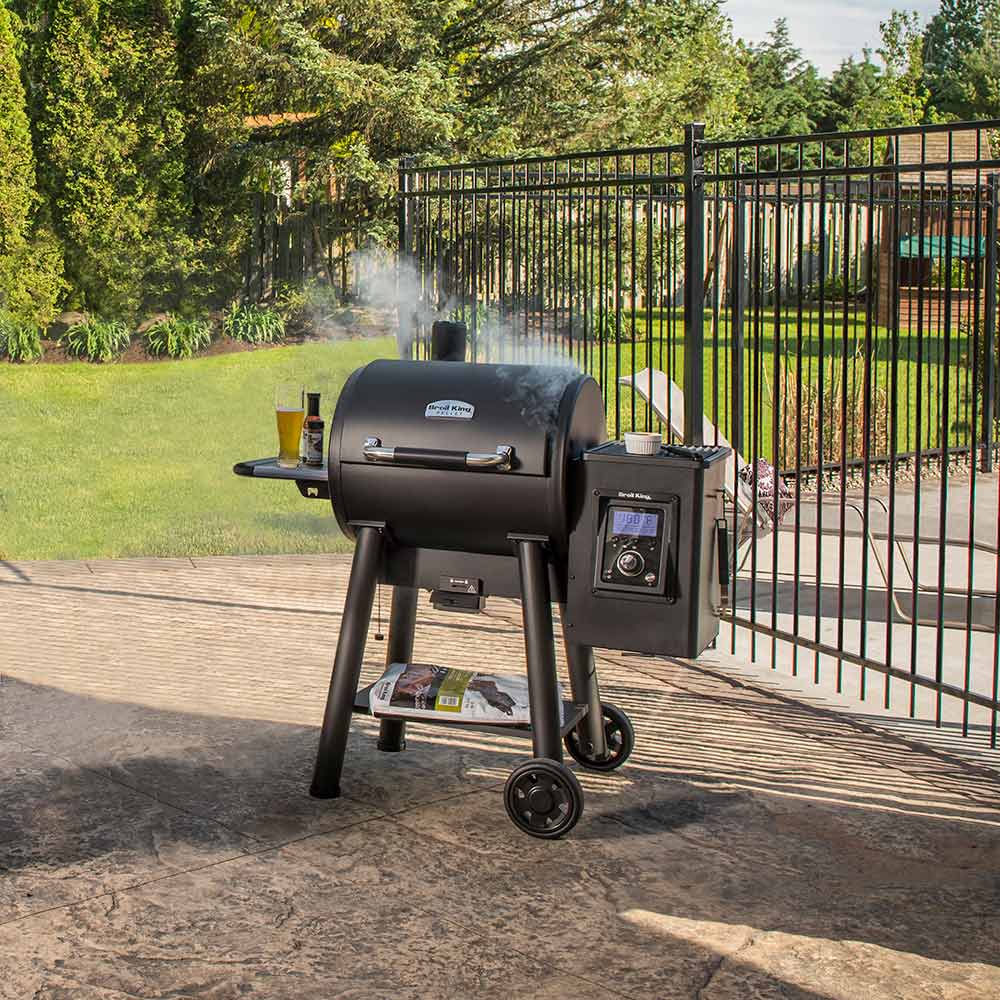 Pellet smoker and grill in black on outdoor patio with front control panel