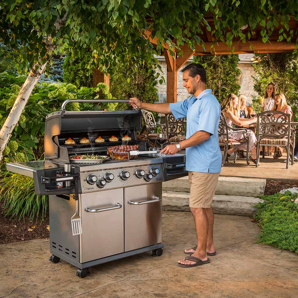 Stainless steel gas grill with side shelves and control knobs on patio