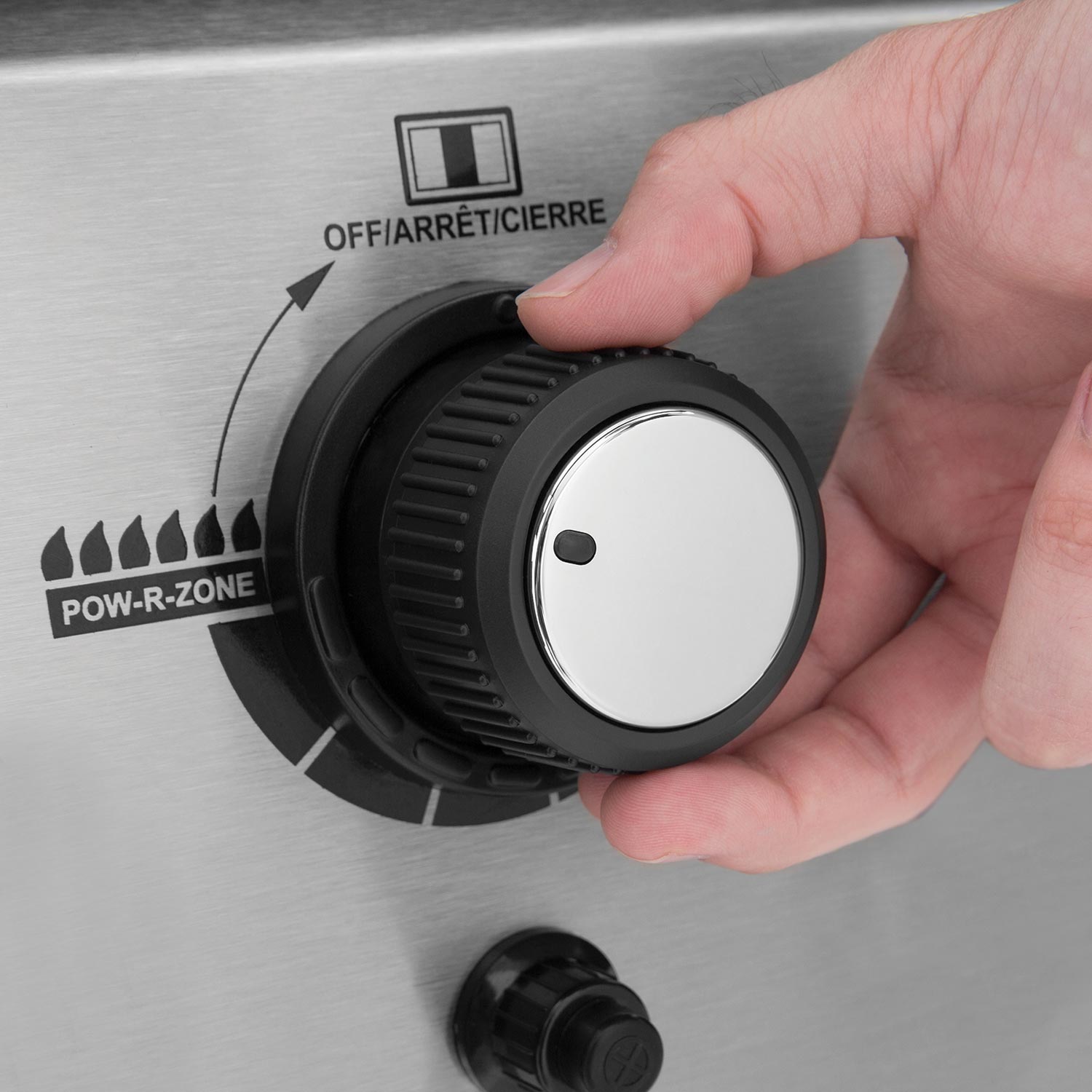 Gas grill control knob dial being turned by hand on stainless front panel