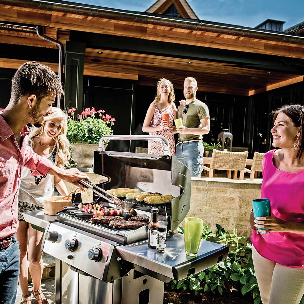 Three-burner gas grill with lid open and food cooking on the grates