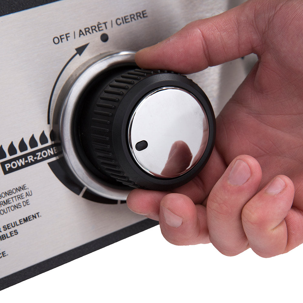 Gas smoker temperature dial being turned by hand