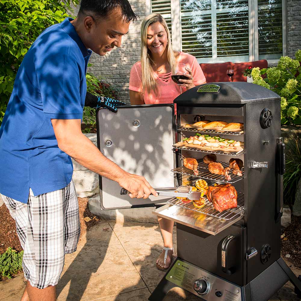 Vertical gas smoker in use with food on racks and open front door