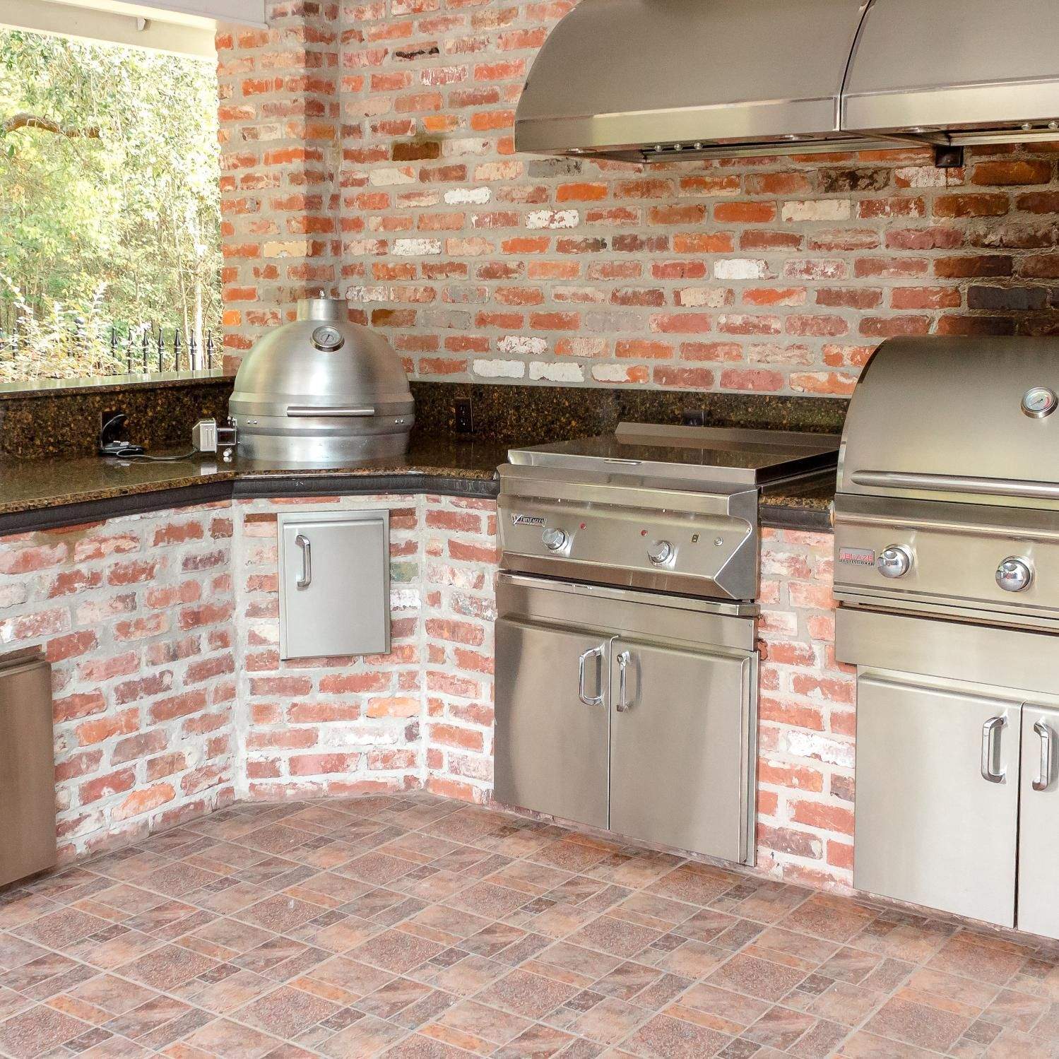 Outdoor built-in grill island with stainless cabinets and integrated kamado grill